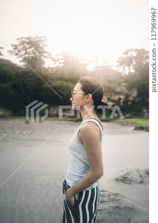 Young Japanese woman wearing sunglasses on a windy sandy beach Young Japanese woman wearing sunglasses on a windy sandy beach 117969967