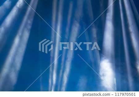 Abstract blue background with white smoky rays of light from stage spotlights. Abstract blue background with white smoky rays of light from stage spotlights. 117970501