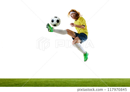 Young woman, soccer player, mid-flight, aiming precise kick at ball, showcasing agility and focus on green stadium against white studio background. Young woman, soccer player, mid-flight, aiming precise kick at ball, showcasing agility and focus on green stadium against white studio background. 117970845