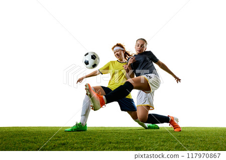 Two young athletic women, soccer players in their 20s, engaged in close tackle on soccer field, both intensely focused on winning ball 117970867
