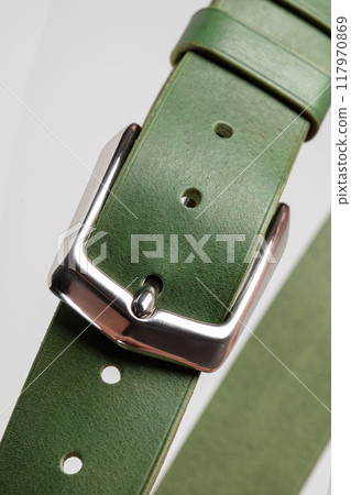 Part of a green leather classic belt with a buckle on a gray background. 117970869