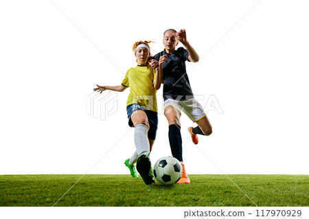 Two determined women, mid-20s, soccer players, captured mid-stride on green field, each pushing their limits in fast-paced, competitive match. Two determined women, mid-20s, soccer players, captured mid-stride on green field, each pushing their limits in fast-paced, competitive match. 117970929