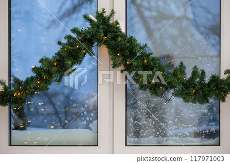 Part of a plastic window decorated with a Christmas garland. Part of a plastic window decorated with a Christmas garland. 117971003