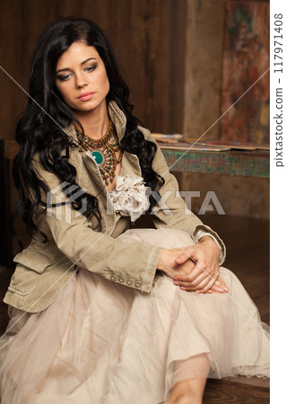 Fashionable brunette woman posing in art studio. Young lady with long curly hair and make-up  117971408