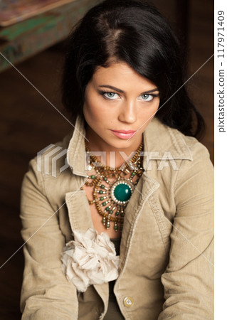 Charming brunette woman posing in art studio. Young lady with long curly hair and make-up Charming brunette woman posing in art studio. Young lady with long curly hair and make-up 117971409