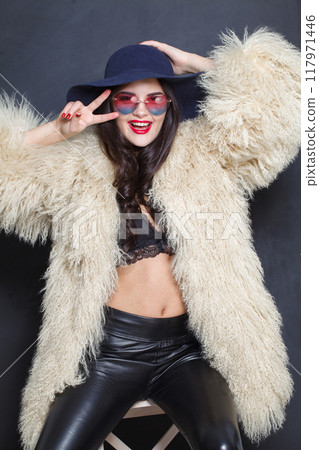Happy woman with red lips make-up and long wavy hair wearing blue hat  117971446