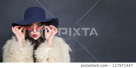 Cheerful woman with red lips make-up and long wavy hair wearing blue hat Cheerful woman with red lips make-up and long wavy hair wearing blue hat 117971447