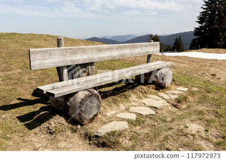 Bench at summit cross of Rechelberg mountain in springtime, Bavaria, Germany 117972973