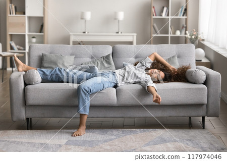 Woman lying sprawled out on sofa in a relaxed position 117974046