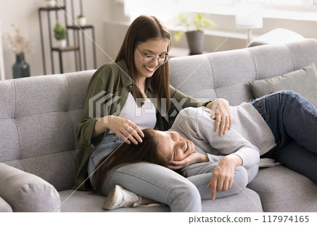 Loving teenager daughter and mother relaxing on sofa 117974165