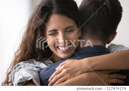 Closeup face view of beautiful wife tightly cuddling her husband Closeup face view of beautiful wife tightly cuddling her husband 117974174