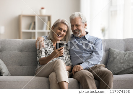 Older spouses using smartphone laughing, watching funny videos 117974198