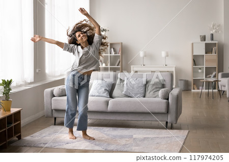 Carefree woman dancing alone in living room 117974205