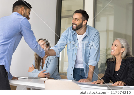 Happy businessmen in casual shaking hands at corporate meeting 117974210