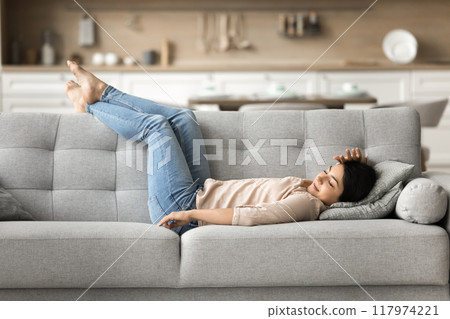 Serene Indian woman enjoy daytime nap lying on comfy sofa 117974221