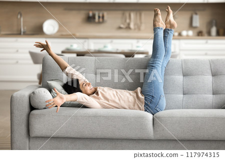 Happy woman enjoys relaxation lying on couch after daytime nap 117974315