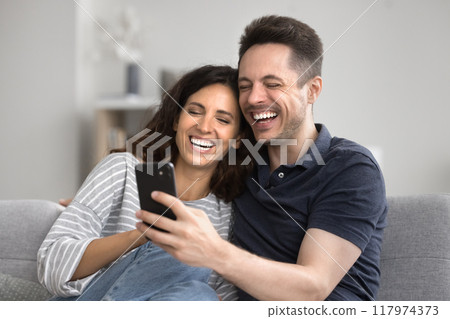 Spouses read happy news, laughing on funny content using smartphone 117974373