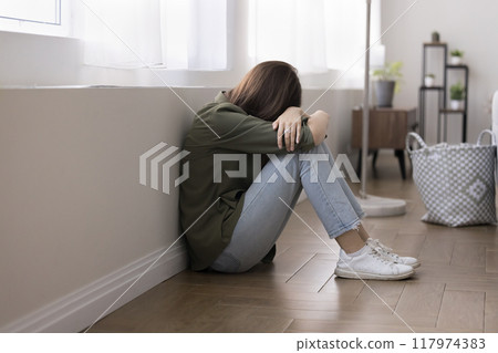 Teen girl crying seated on floor, suffers from bullying Teen girl crying seated on floor, suffers from bullying 117974383