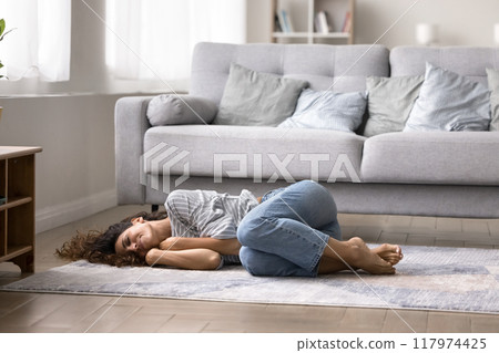 Woman fell asleep on floor curled up in soft rug Woman fell asleep on floor curled up in soft rug 117974425