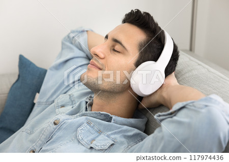 Happy peaceful Latin man in wireless headphones listening to music Happy peaceful Latin man in wireless headphones listening to music 117974436