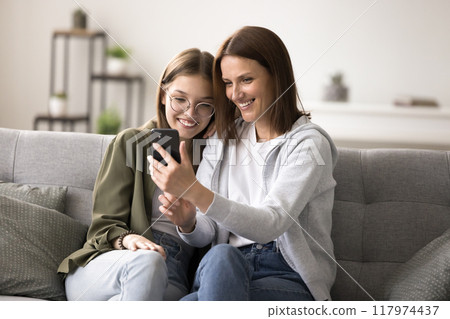 Teenager girl spend time with mother use mobile phone 117974437
