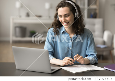 Beautiful student girl in headphones watching educational videos on internet Beautiful student girl in headphones watching educational videos on internet 117974507