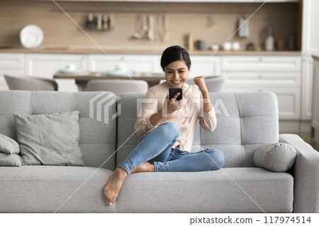 Happy young woman receives good news on mobile phone Happy young woman receives good news on mobile phone 117974514