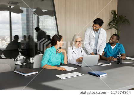 Group of smiling general practitioners discussing work-related issues using laptop 117974564