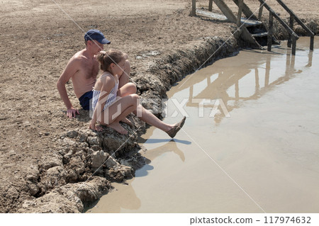 Happy father and daughter resting on mud geyser resort with therapeutic mud outdoors 117974632