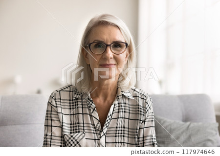 Headshot woman in glasses sit on sofa looking at camera 117974646