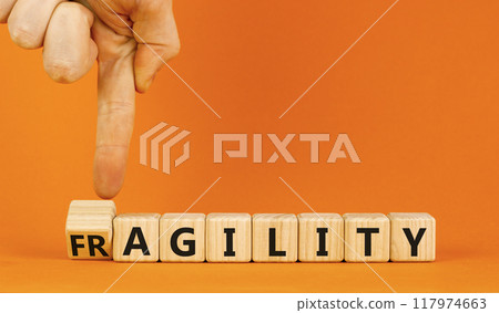 Fragility or agility symbol. Concept words Fragility and Agility on wooden cubes. Beautiful orange table orange background. Businessman hand. Business fragility and agility concept. Copy space. Fragility or agility symbol. Concept words Fragility and Agility on wooden cubes. Beautiful orange table orange background. Businessman hand. Business fragility and agility concept. Copy space. 117974663