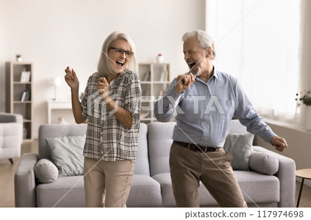 Happy retired couple dancing in cozy living room Happy retired couple dancing in cozy living room 117974698