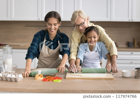 Cute helper kid girl helping mom and grandma to bake 117974766