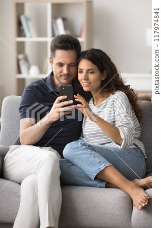 Married couple spend time sitting on sofa use smartphone Married couple spend time sitting on sofa use smartphone 117974841