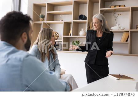 Senior female boss talking to younger employees in meeting room 117974876