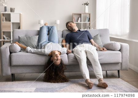 Sleeping young couple lying upside down on sofa 117974898