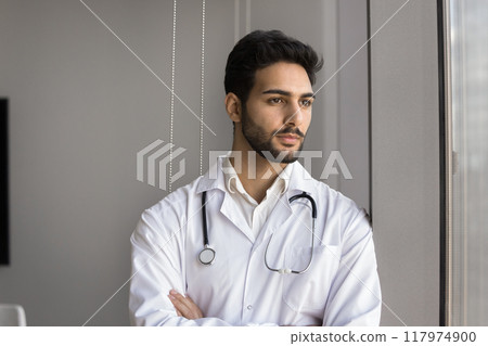Arabic male doctor looking pensively out window 117974900