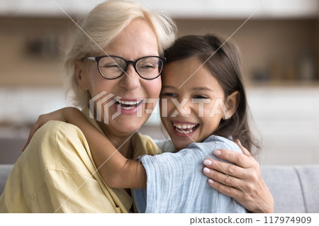 Joyful granddaughter and granny hugging with faces touch 117974909