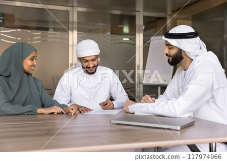 Successful young Arabian business partners signing contract at meeting 117974966