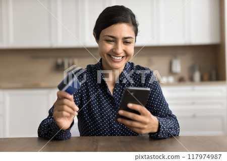 Smiling young woman hold mobile phone and credit card 117974987
