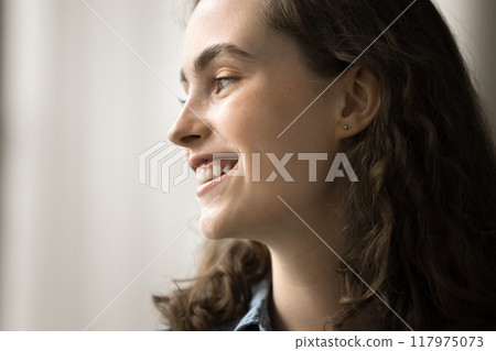 Dreamy beautiful young woman with candid smile looking into distance Dreamy beautiful young woman with candid smile looking into distance 117975073