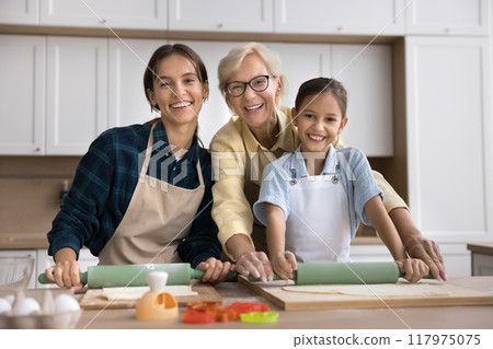 Happy girls and women of three generations baking pastry together Happy girls and women of three generations baking pastry together 117975075