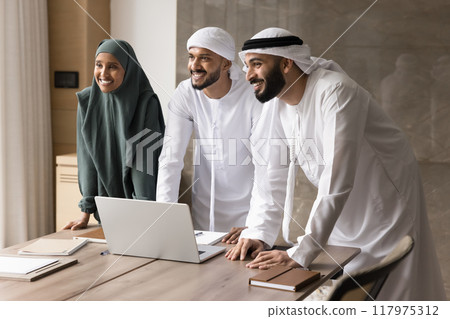 Cheerful young Middle Eastern business colleagues standing at meeting table Cheerful young Middle Eastern business colleagues standing at meeting table 117975312