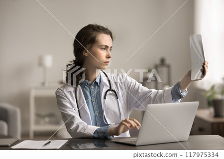 Internist holding X-ray results, review fractures of patient 117975334