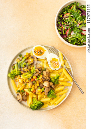 Pasta with fried mushrooms and broccoli, green peas and corn, fresh mix salad Pasta with fried mushrooms and broccoli, green peas and corn, fresh mix salad 117975365