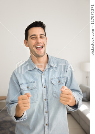 Happy excited young Latin man having fun at home Happy excited young Latin man having fun at home 117975371