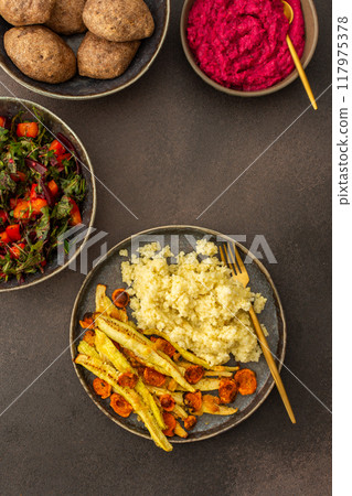 Enjoy a hearty breakfast or lunch with millet, baked zucchini, and carrots, paired with a fresh salad of seasonal vegetables and herbs, chickpea buns, beetroot hummus for a delicious vegetarian meal 117975378