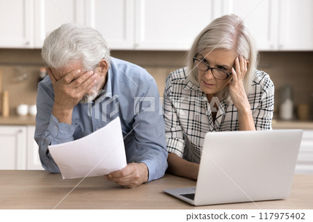 Stressed elderly couple reading awful news from bank Stressed elderly couple reading awful news from bank 117975402