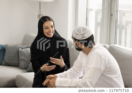 Cheerful Muslim couple talking and laughing at home Cheerful Muslim couple talking and laughing at home 117975710