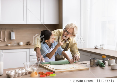 Playful cute granddaughter kid touching face of happy laughing grandma 117975715